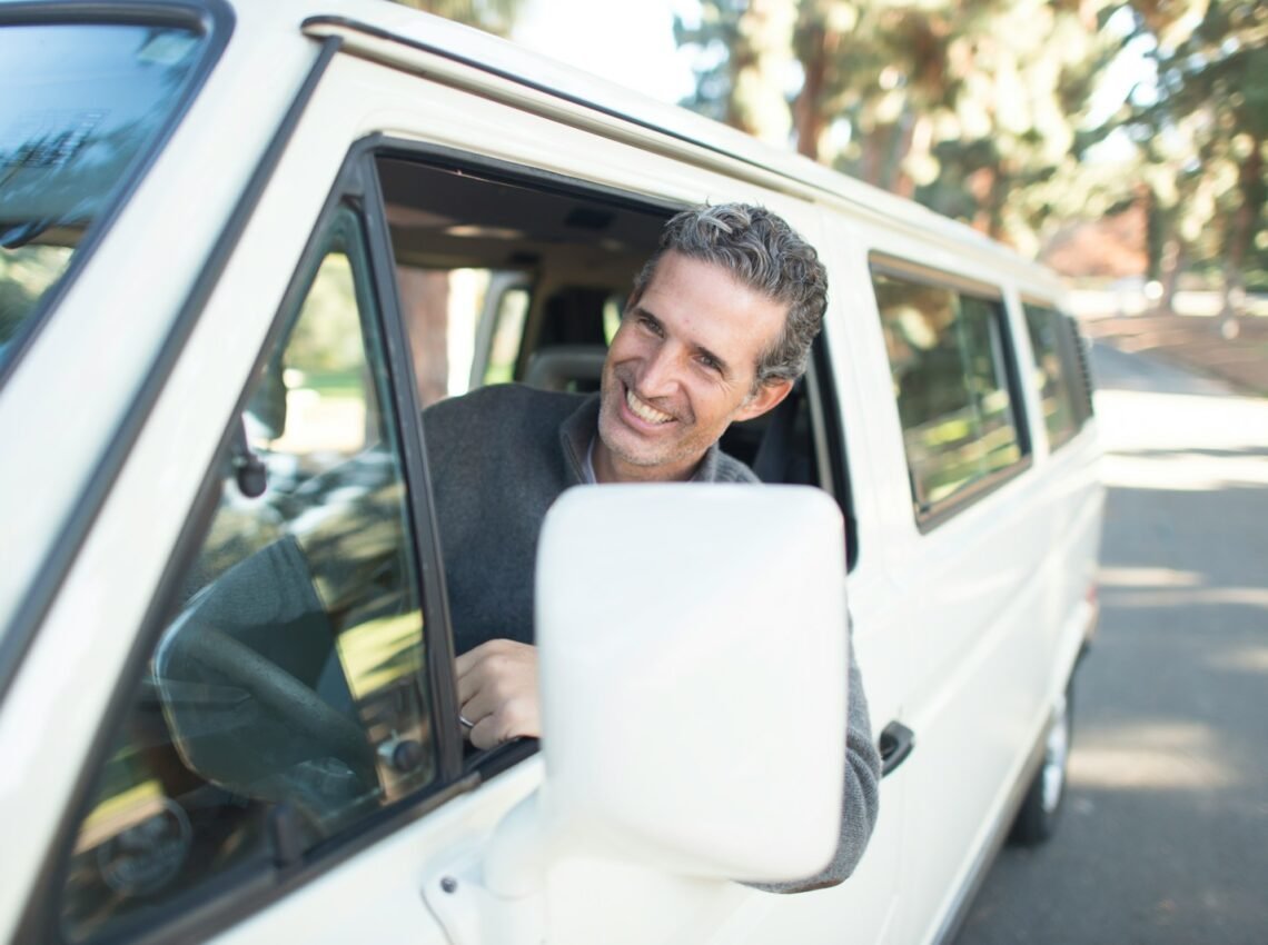 man in gray sweater leaning on van window